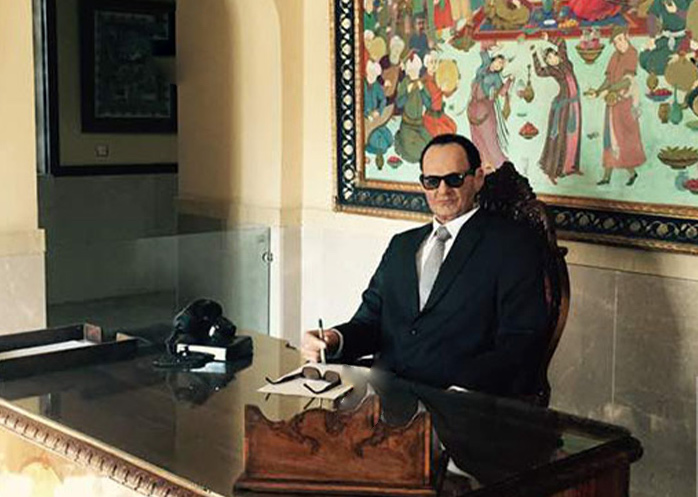 Eisa Bahadori at his desk before a Persian miniature.