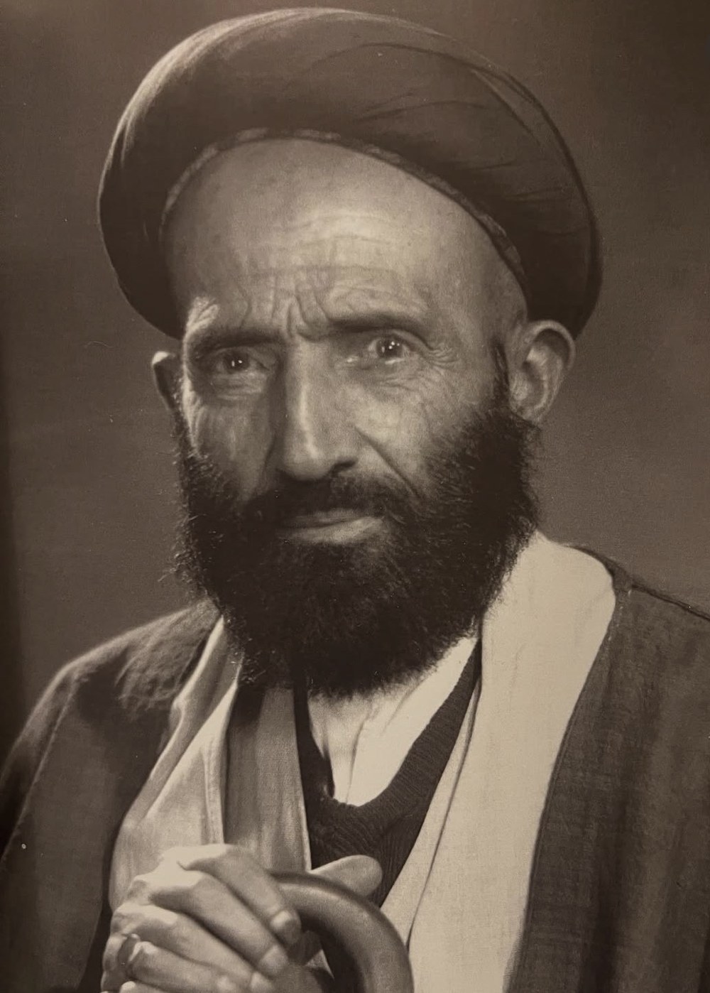 Mirza Agha Emami in later life: white-bearded, in the sadat turban, hands resting on a cane.