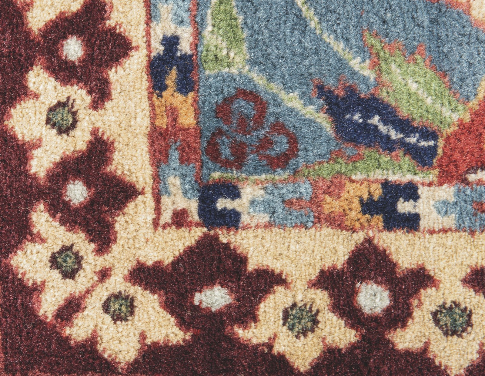 A close detail of a PETAG carpet showing the woven çintamani mark: three small roundels clustered in a triangle within the field