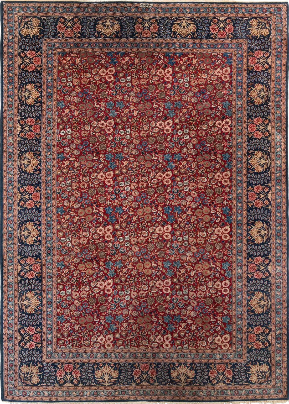 A Kashan carpet with a deep red field densely covered in small-scale floral sprays and palmettes, framed by a midnight-blue border of flowering plants; signed in a cartouche at the top