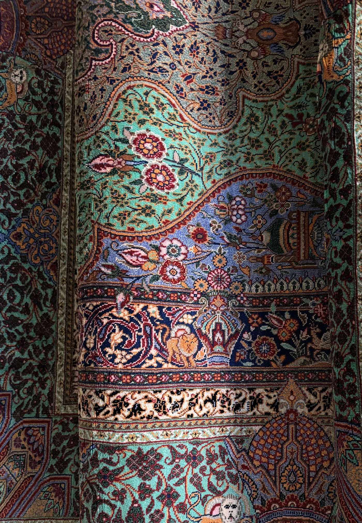 Detail of a Mohammad Jamshidi all-silk Qom carpet from the Gereh & Naqsh collection, showing the dense pictorial border and pile sheen