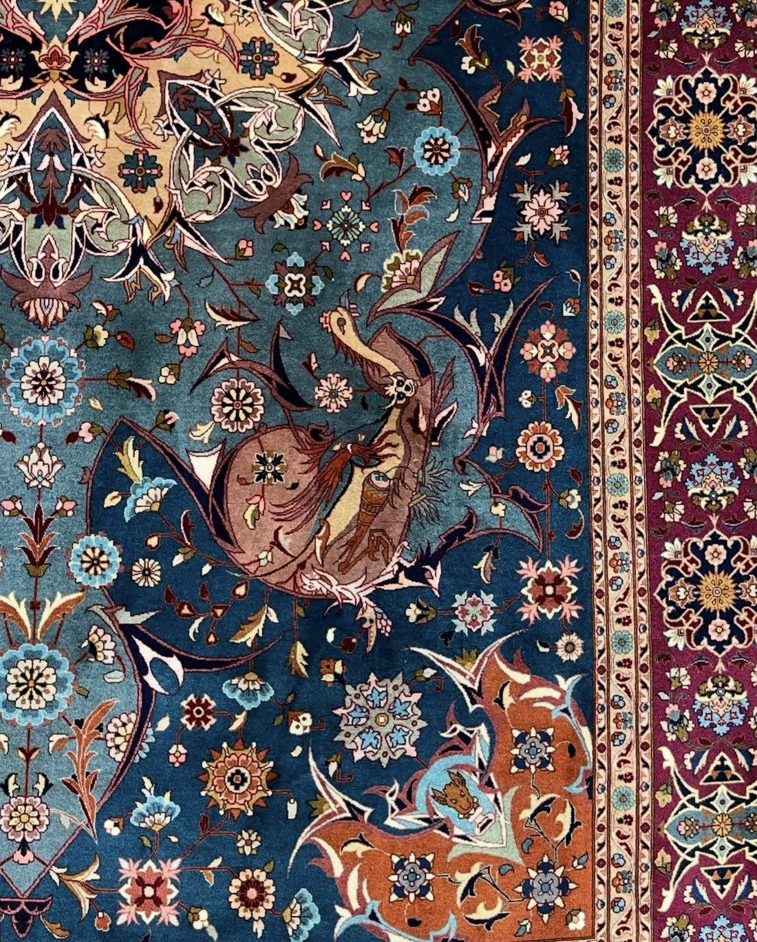 Detail of a mid-twentieth century Ahmad Emad Tabriz carpet, showing a pictorial figure on a teal-blue floral field within a magenta border