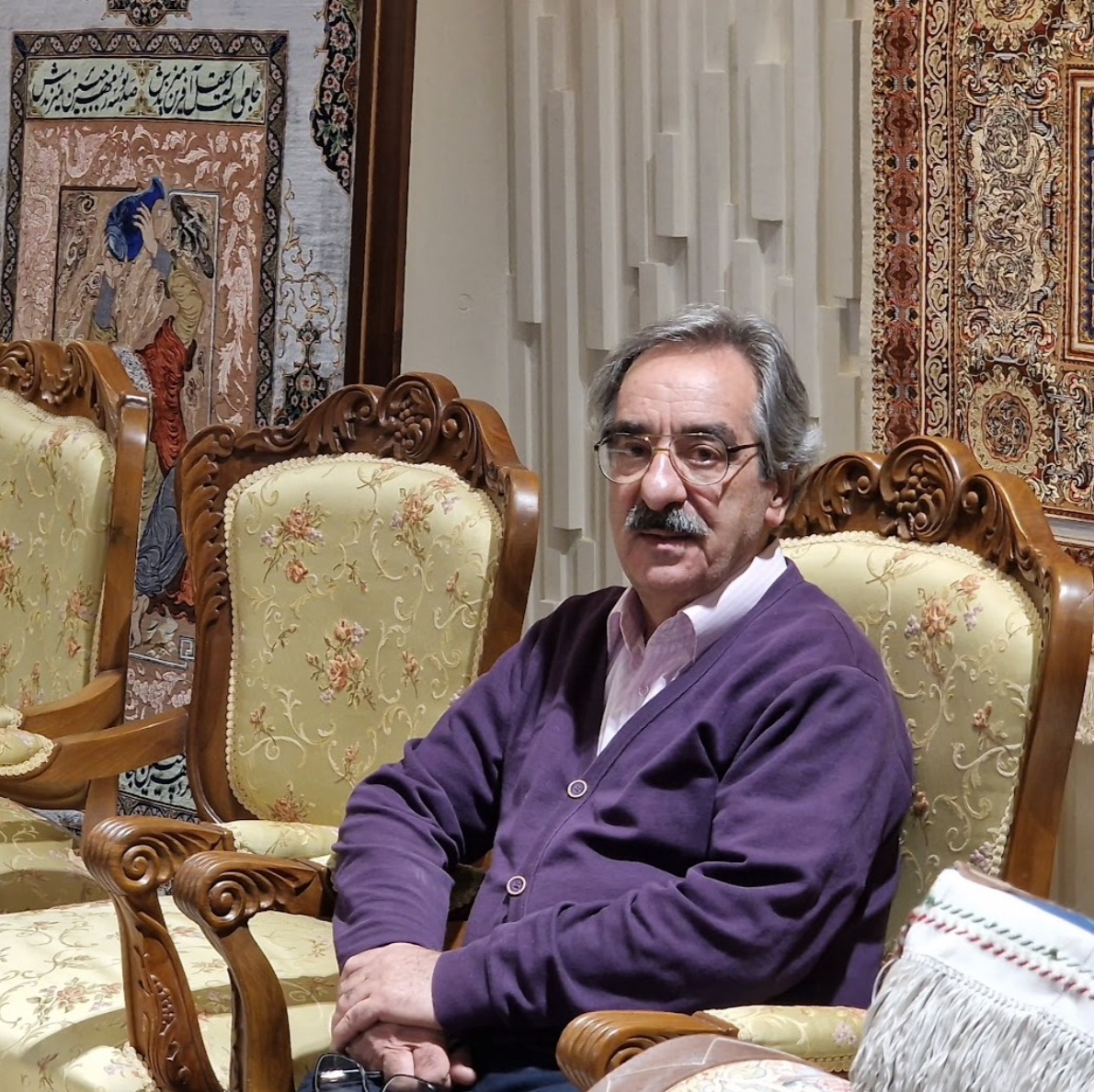 Akbar Mahdiei seated among his carpets.