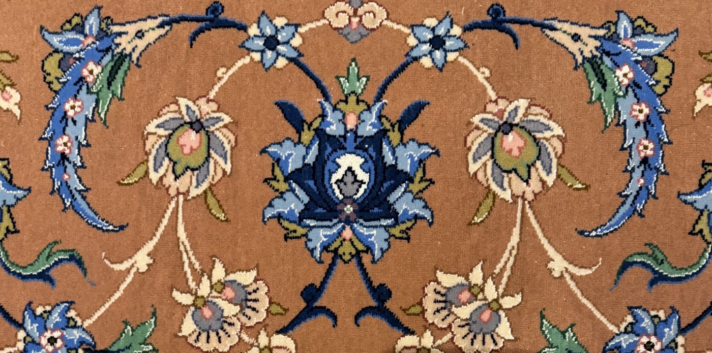 The terracotta-ground border at close range, a band of palmette and scrolling vine worked in blue, green, and cream.