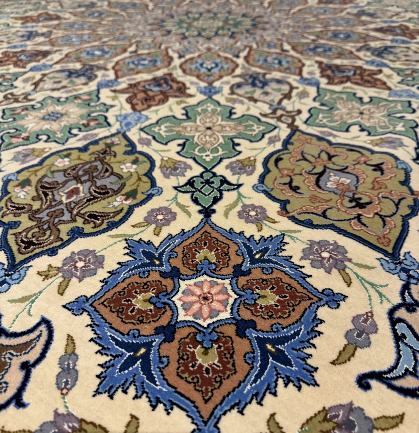 The field rising toward the domed medallion, seen at a low angle so the silk pile catches the light against the wool ground.