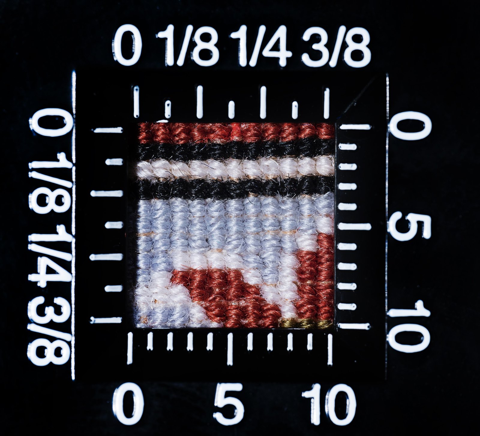 Macro photograph of the carpet’s knotting against a calibrated rule, showing the fineness of the asymmetric knots on a silk foundation.