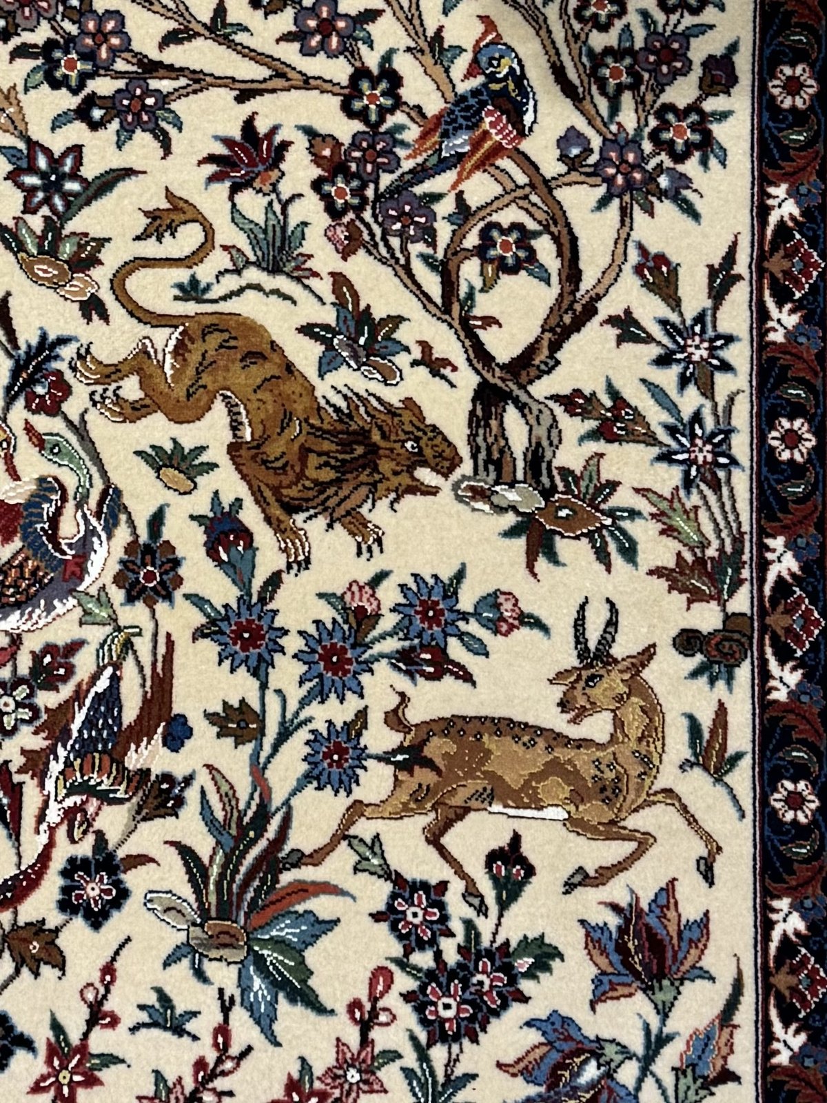 A close detail of the hunting scene: a tiger in pursuit, a spotted gazelle leaping, and a perched bird among flowers.