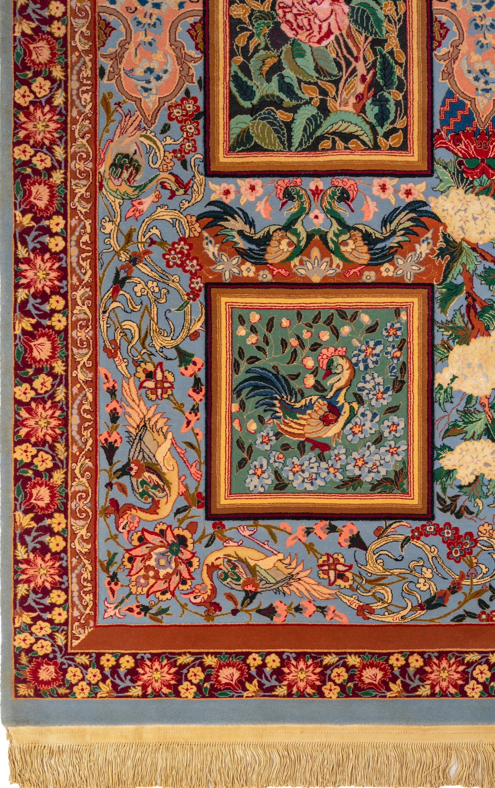 A corner of the carpet, showing the red floral border, the silk fringe, and the relief of the field.