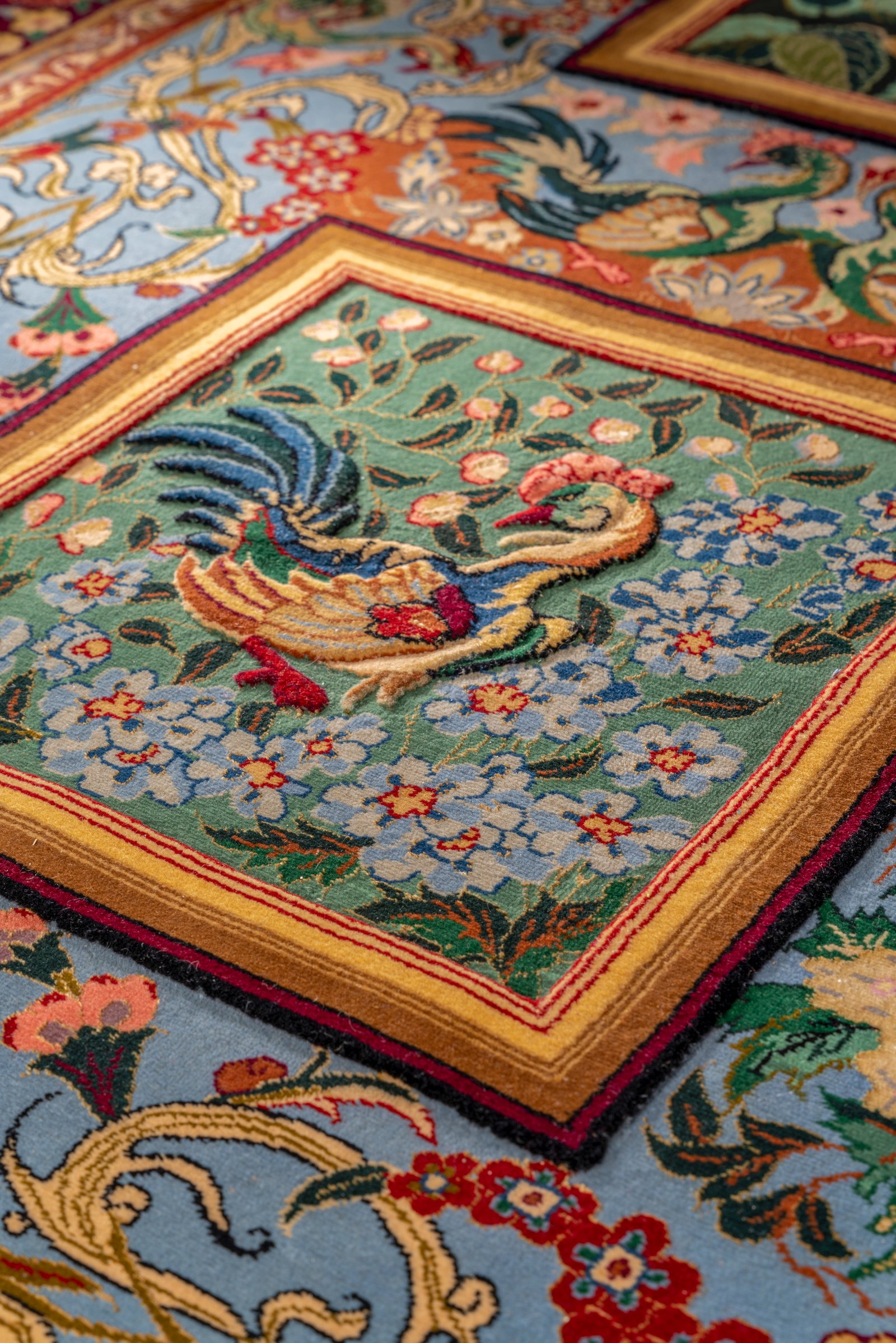 A game-bird panel in close view, the bird and blossoms carved in relief so the pile stands proud of the green ground.