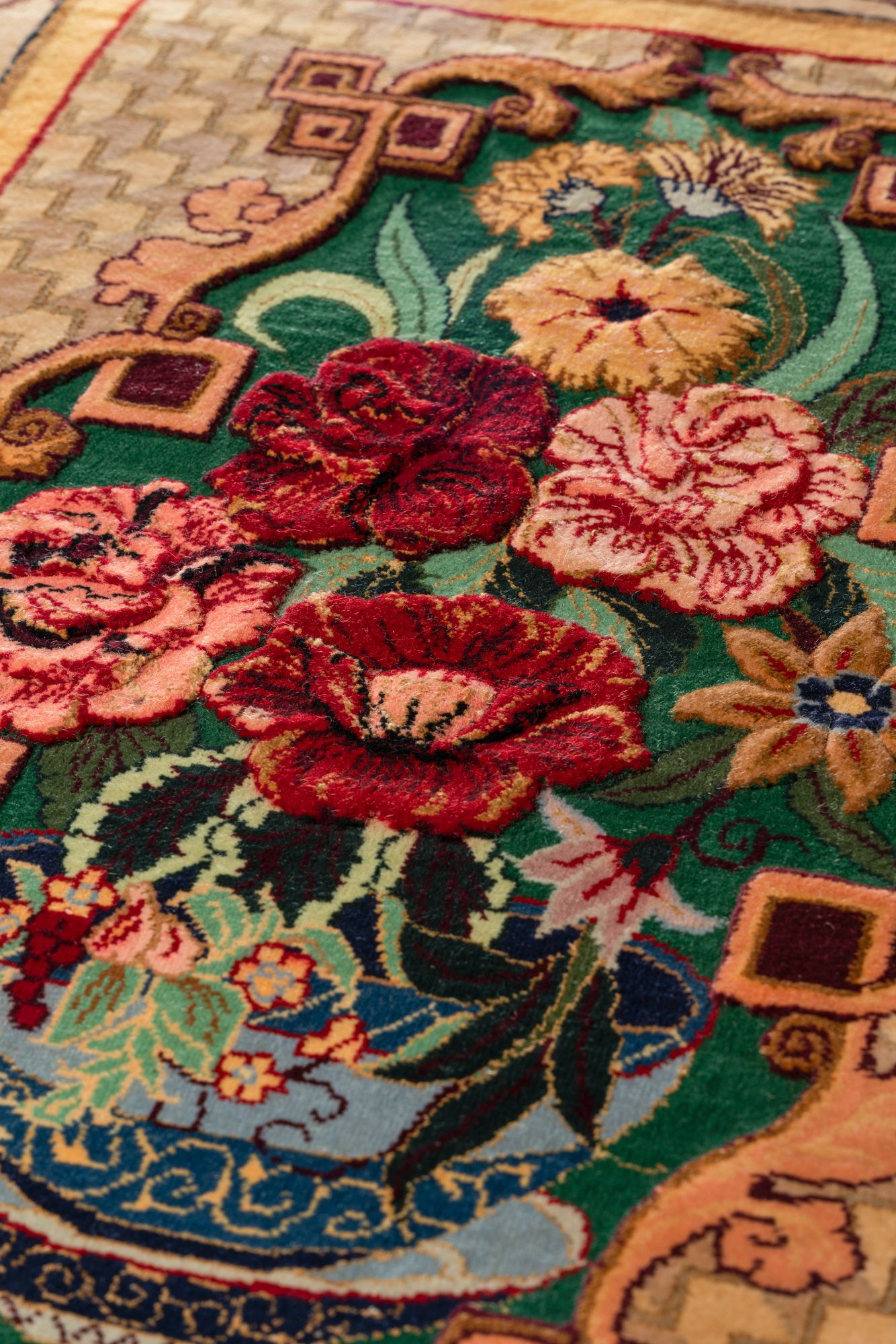 Macro of the Gold Qajar Door showing the barjasteh sculpted relief: roses and poppies raised in carved pile, standing proud of the green ground.