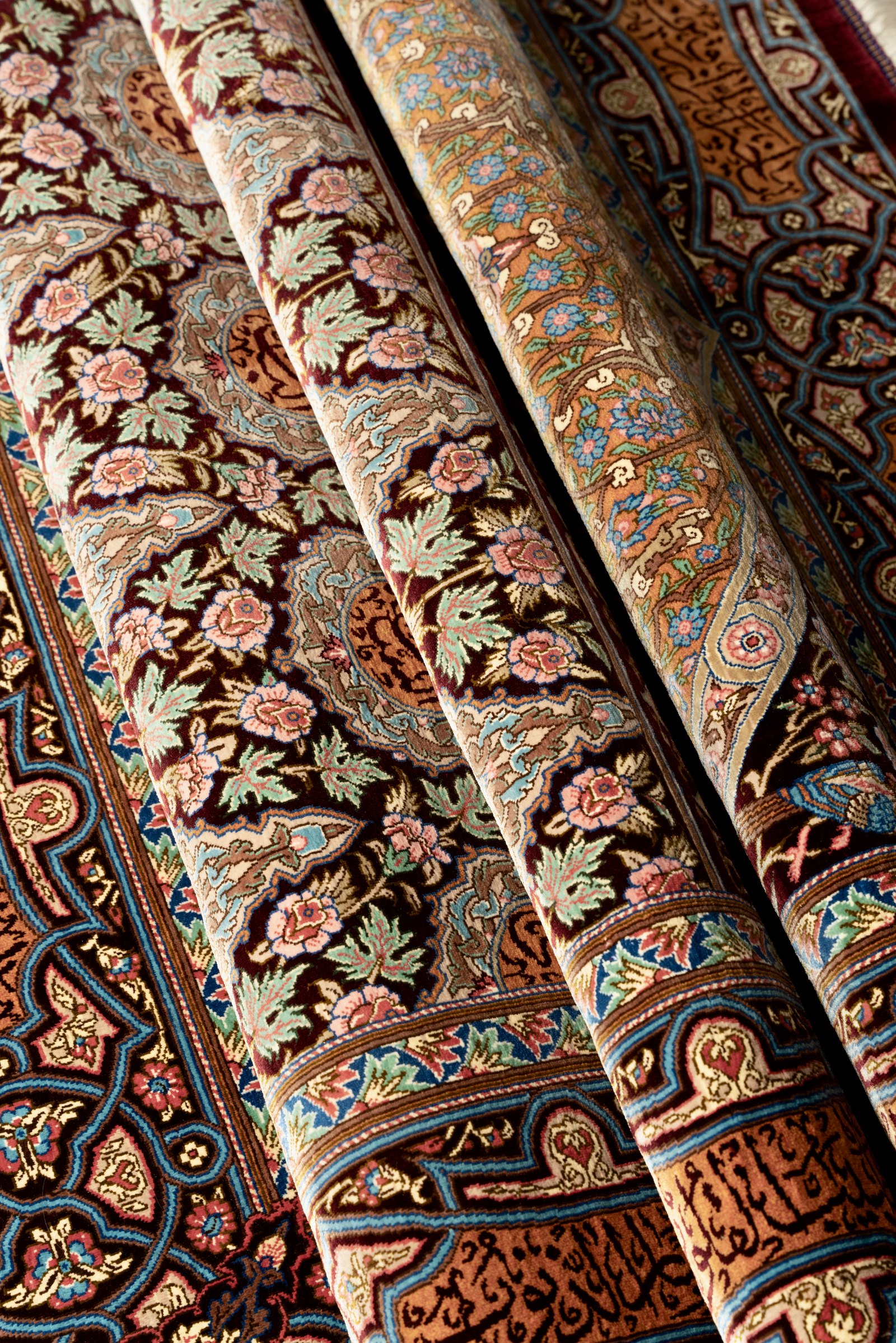 The silk pile at an angle, the colour and sheen shifting in the light across the woven calligraphy and floral work.