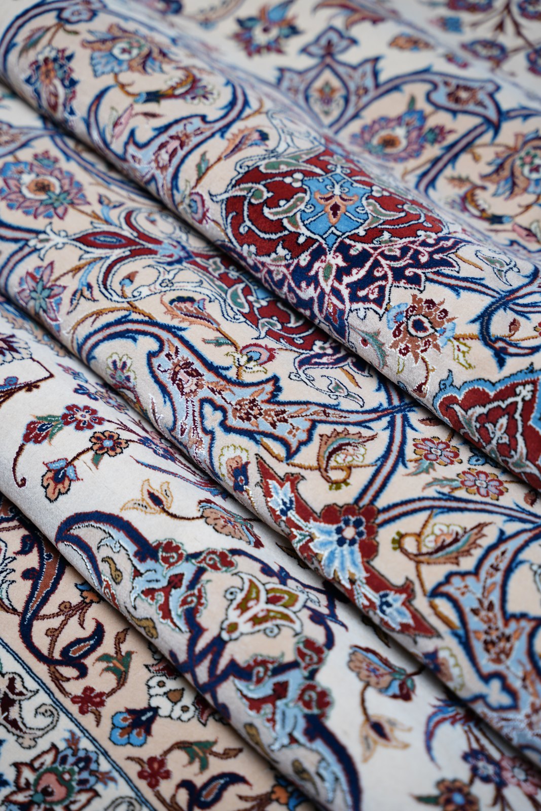 Folded runs of the field: scrolling stems, serrated leaves and blossoms in madder, blues and sage on ivory.