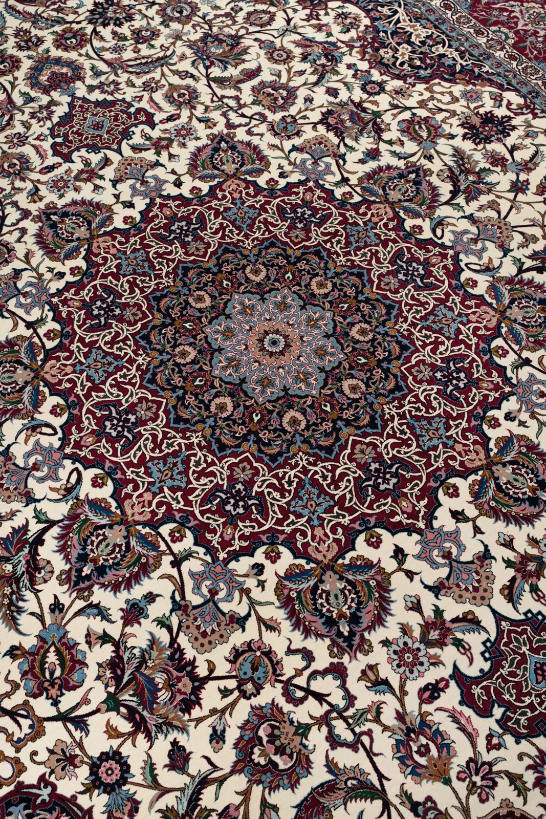 The many-lobed star medallion at an angle, its rings of madder, navy and light blue resolving into the ivory field.
