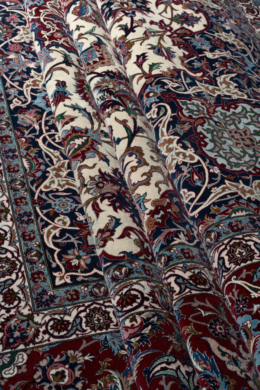 The carpet in soft folds, the wool pile catching the light along each crest.