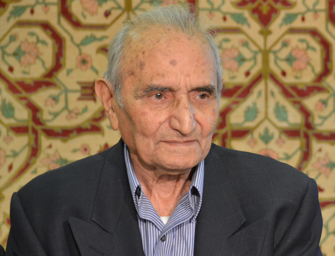 Ali Rashtizadeh photographed beside one of his Qom silk carpets.