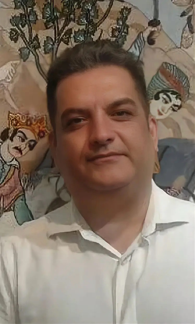 Mehdi Saeedi photographed before one of his figural carpets.