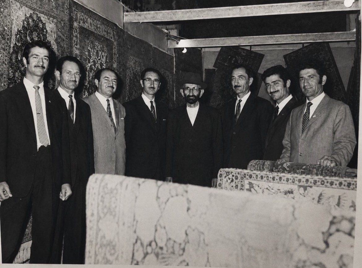 Haj Reza Seirafian at center with his seven sons, before a wall of carpets.