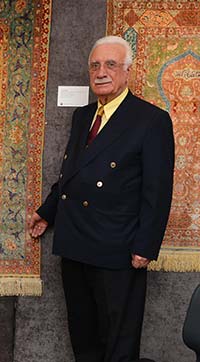 Avak Şirinoğlu standing before his Hereke silk carpets.